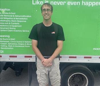 Male standing in front of a green truck.