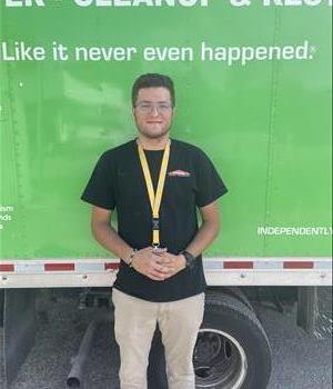 Male standing behind a green truck.