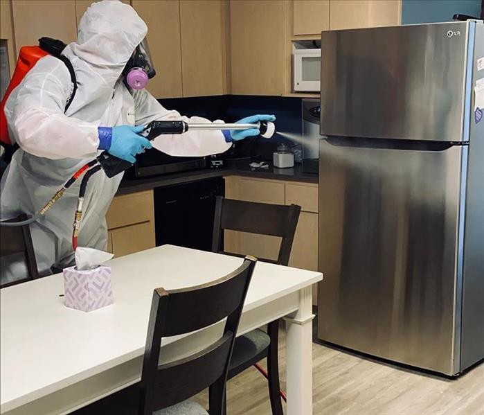 man in white tyvek suit sanitizing kitchen 